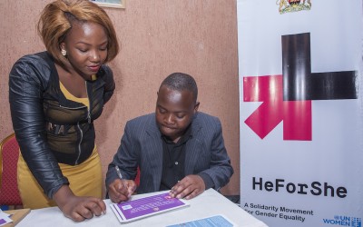 A journalist, Harold Kapindu signs the HE FOR SHE campaign form in support of gender equality as UN Women volunteer, Hope Matilda Mawerenga, watches during the premiere of "Mercy's Blessing".